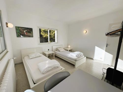 Cette chambre blanche comprend deux lits et un canapé. dans l'établissement Haut de villa, pleine vue mer, à Saint-Mandrier-sur-Mer