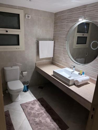 a bathroom with a sink and a mirror and a toilet at A Luxury Hotel Appartment at NEW GIZA Imperial Compound قريبة جدا للمتحف المصري الجديد in Abū Rawwāsh