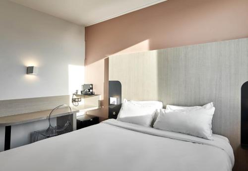 a bedroom with a large bed with white pillows at B&B HOTEL Paris Nord Gonesse Parc des Expos in Gonesse