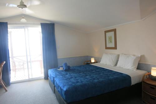 um quarto com uma cama grande e um cobertor azul em The Sunset em Flying Fish Cove