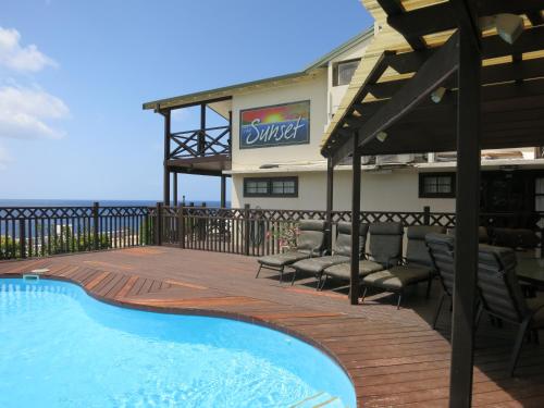 a resort with a swimming pool and chairs and a building at The Sunset in Flying Fish Cove