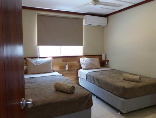 a hotel room with two beds and a window at The Cocos Padang Lodge in Flying Fish Cove