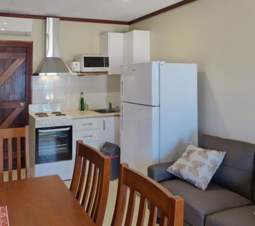 a kitchen with a couch and a white refrigerator at The Cocos Padang Lodge in Flying Fish Cove