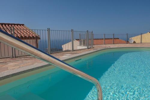 a swimming pool next to a fence with a blue water at Appartamento il Delfino - Beach House in Isola Rossa