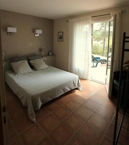 une chambre avec un lit et une porte coulissante en verre dans l'établissement Maison calme sur terrain arboré et piscine privée, à Vagnas