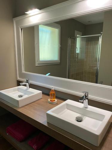une salle de bain avec deux lavabos et un grand miroir dans l'établissement Maison calme sur terrain arboré et piscine privée, à Vagnas