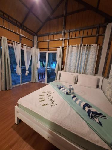 a bedroom with a large bed in a room with windows at Baan Suan Kayoo 1 Long beach Aow Yai in Ko Phayam