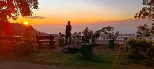 a man standing in front of the sunset at Bel View Guest House in Haputale