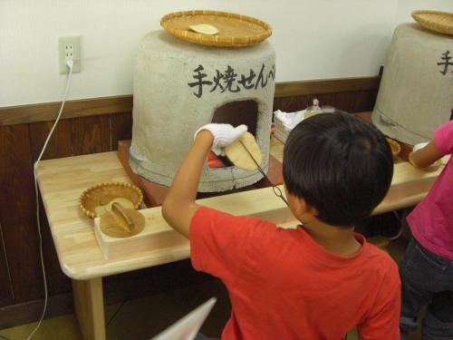 a young boy is making a cake in a kitchen at Spa Hotel Alpina Hida Takayama in Takayama