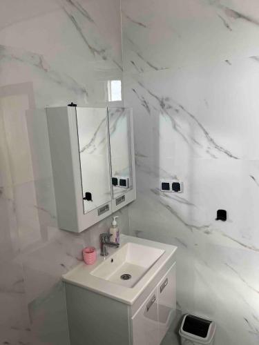 a white bathroom with a sink and a mirror at Dar Manzily in Draïd