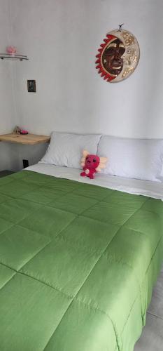 a green bed with a teddy bear sitting on it at Casa Amarilla Tecámac in Santa Cruz Tecamac