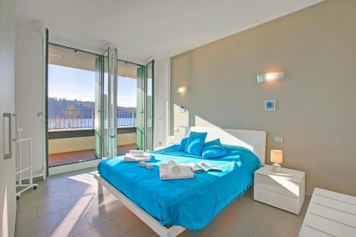 a bedroom with a blue bed with a large window at Sogno Sul Lago Lake Front - Happy Rentals in Laveno-Mombello