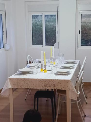 a white table with white plates and glasses on it at Casa dos pássaros in Carril