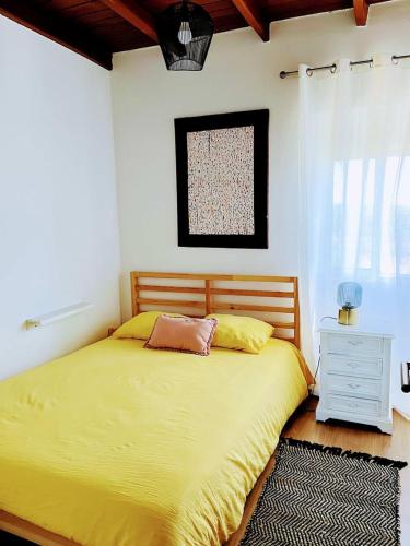 a bedroom with a large yellow bed and a window at Casa dos pássaros in Carril