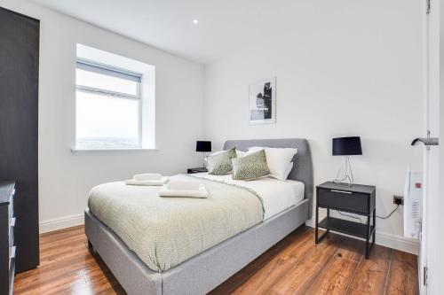 a white bedroom with a bed and a window at Host & Stay - Canalside Lofts Apartment in Burnley