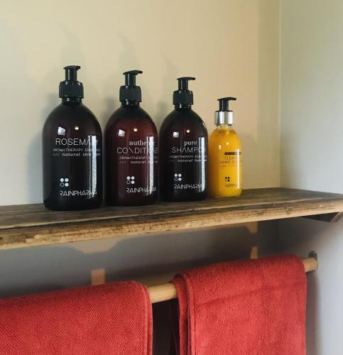 a shelf with four bottles of soap and a red chair at Panacée Guesthouses in Ronse