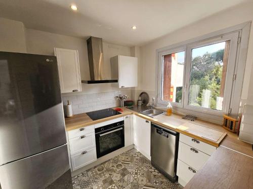 d'une cuisine équipée d'appareils en acier inoxydable et d'une fenêtre. dans l'établissement Bel appartement, climatisation, WIFI, plage et commerces à pied, à La Seyne-sur-Mer