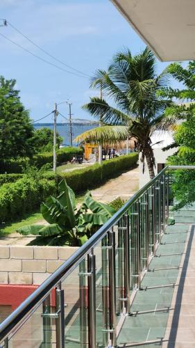 a balcony with a palm tree and a sidewalk at Cabaña La Roca in San Antero