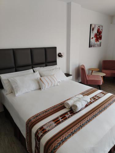 a bedroom with a large white bed with towels on it at Casa Yuraq Hotel Boutique in Chincha Alta