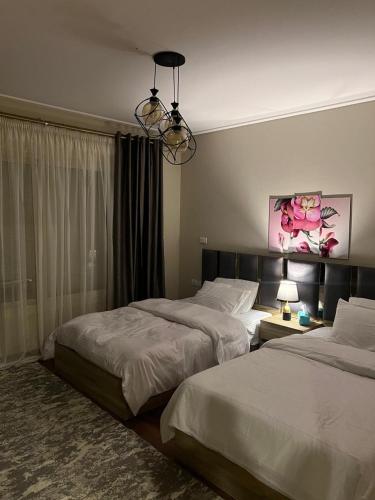 a bedroom with two beds and a chandelier at شقة فندقية نيو جيزة الشيخ زايد in Abū Rawwāsh