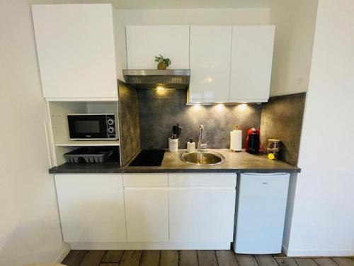 a kitchen with white cabinets and a sink at Le Studio de Théa - Private Parking - 2 Guests in Le Mans