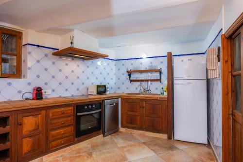 a kitchen with wooden cabinets and a white refrigerator at Es Mercat in Sóller