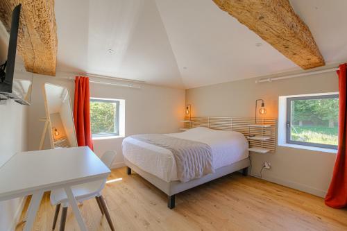 a bedroom with a bed and a desk and two windows at Chambre Comfort - Ancien Cuvage des Pierres Dorée in Denicé