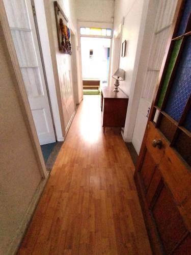 a hallway with a wooden floor and a table and a door at Hostal Perro Watón in Valparaíso