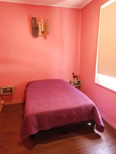 a pink bedroom with a bed with a purple blanket at Hostal Perro Watón in Valparaíso