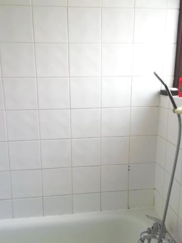 a white tiled bathroom with a bath tub at 42 Churchbury Rd, Room 3 in Eltham