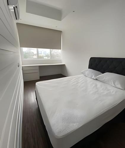 a white bed in a room with a window at 506 Alphaville Link Studio in Aldeia