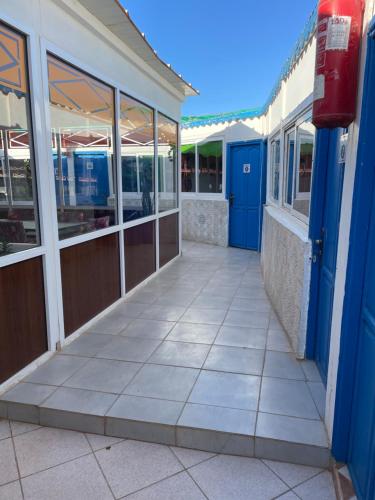 a building with blue doors and a tile sidewalk at Au soleil couchant in Mirleft