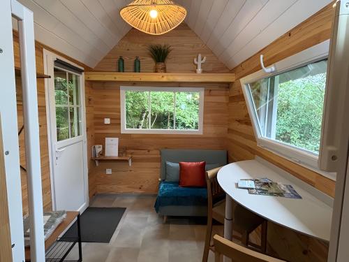 une petite maison avec un canapé bleu et une fenêtre dans l'établissement Tiny House au coeur de la nature, à Bessuéjouls