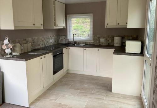 a kitchen with white cabinets and a tile floor at MOEL SIABOD - GLAN GWNA HOLIDAY PARK in Caernarfon