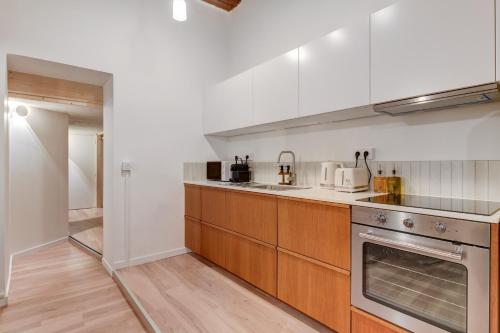 - une cuisine avec des murs blancs et des placards en bois dans l'établissement NOCNOC Le Balme, à Lyon