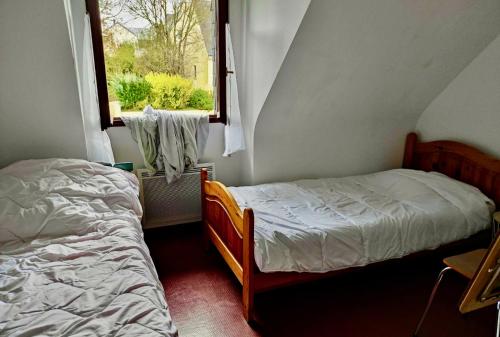une petite chambre avec deux lits et une fenêtre dans l'établissement Maison 6Pers, proche plages et commerces Guidel, à Guidel