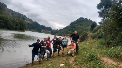 a group of people standing on the side of a river at Higland Homestay Bac Ha in Bắc Hà