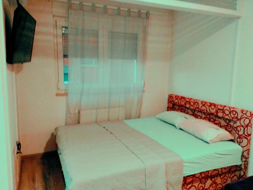 ein Schlafzimmer mit einem Bett und einem Fenster in der Unterkunft Apartman Central in Doboj