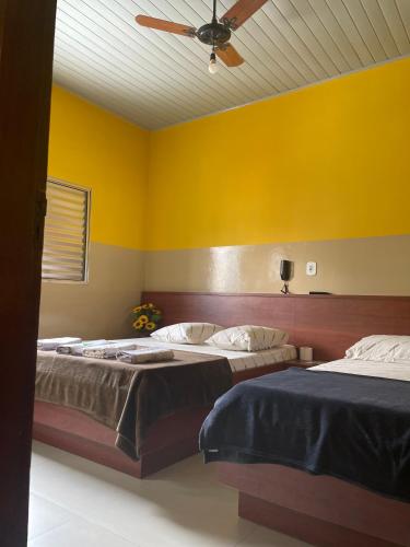 two beds in a room with yellow walls at Hotel Gasometro in Sao Paulo