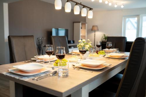 a dining room table with glasses of wine and food at Ferienwohnungen Citylight Winterberg in Winterberg