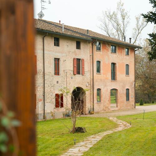 an old brick building with red doors and a yard at Origine Country Farm in Tabiano