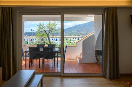 a living room with a sliding glass door with a dining table at Carpe Diem Cadaqués in Cadaqués