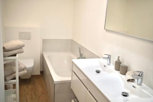 a white bathroom with a sink and a bath tub at Appartement de charme in Vaux-sur-Sûre