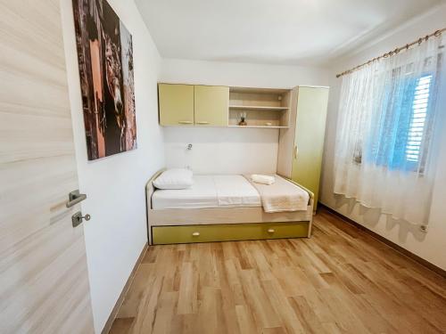a small bedroom with a bed and a window at Apartment Markioli in Povlja