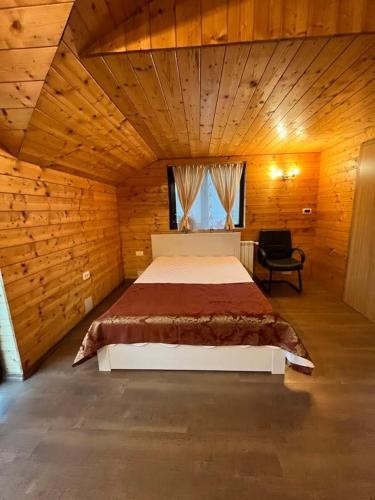 a bedroom with a large bed in a wooden room at Eden Villa in Ocina de Jos