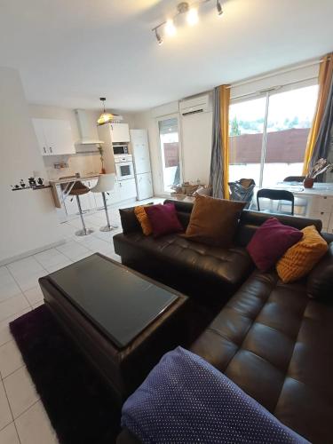 Il comprend un salon avec un canapé en cuir brun et une cuisine. dans l'établissement Grand T2 avec terrasse, à Marseille