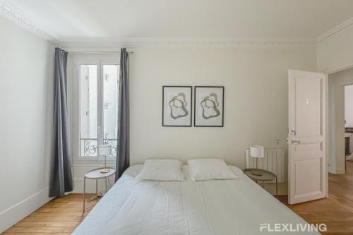 - une chambre blanche avec un grand lit et deux photos sur le mur dans l'établissement Flexliving - whole house - Hoche, à Levallois-Perret