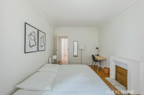 - une chambre blanche avec un grand lit et une cheminée dans l'établissement Flexliving - whole house - Hoche, à Levallois-Perret
