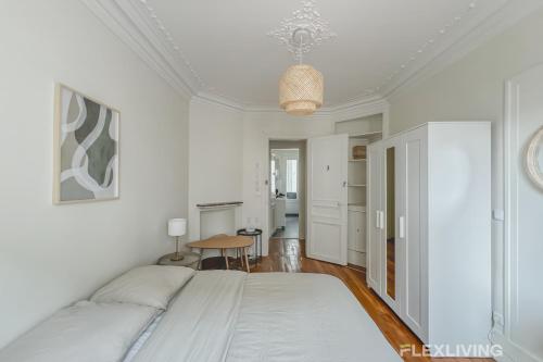une chambre blanche avec un lit et une table dans l'établissement Flexliving - whole house - Gabriel Peri, à Levallois-Perret