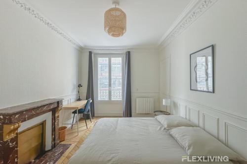 Cette chambre comprend un lit, un bureau et une cheminée. dans l'établissement Flexliving - whole house - Hoche, à Levallois-Perret